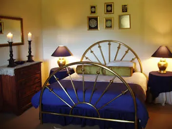 A bedroom with a brass bed blue bedding and two bedside lamps