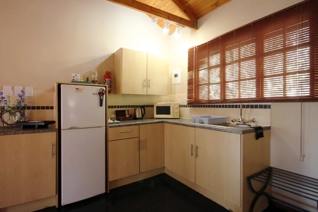 Small kitchen with wooden cabinets white fridge microwave and sink under a window