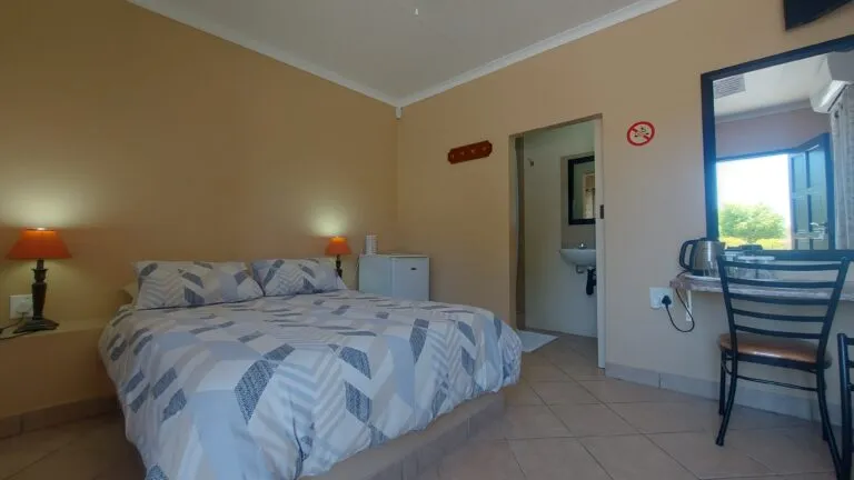 Bedroom with double bed small fridge sink and mirror in a simple setting