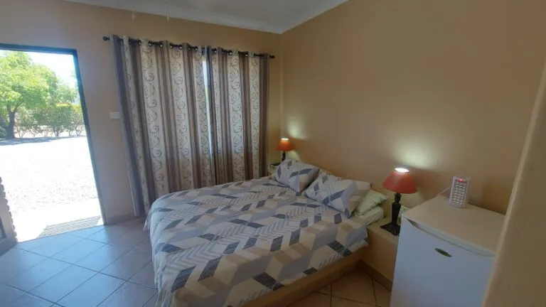 Bedroom with double bed patterned bedding two lamps and open door to outside