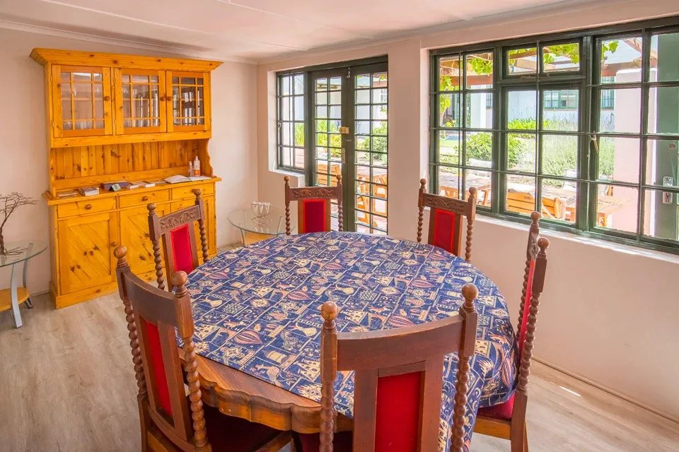 Wooden dining table with red chairs and a patterned tablecloth in a bright room