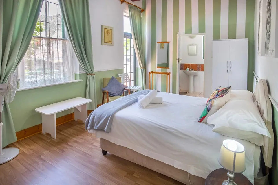 Bedroom with a large bed green curtains and striped wallpaper