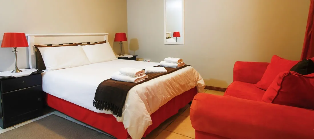 Cozy bedroom with a large bed red couch and bedside lamps