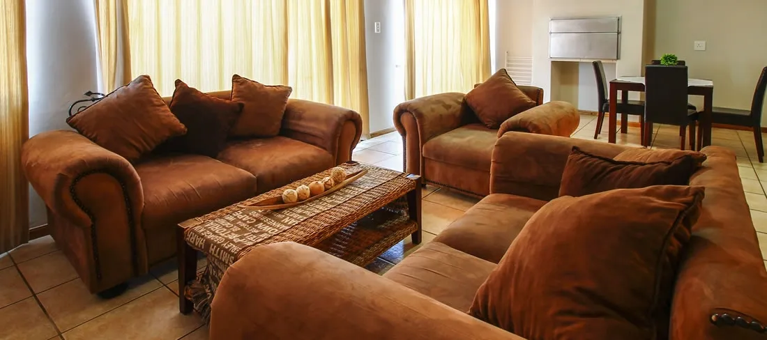 Brown sofas and coffee table in a cozy living room with large windows