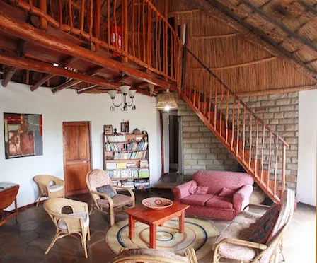 Cozy living room with wooden stairs bookshelves and African decor