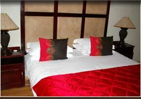 Double bed with red and black pillows and red bedspread in a bedroom