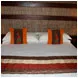 Bed with white sheets orange pillows and wooden headboard in a cozy room