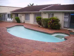 Swimming pool in a backyard with brick paving and surrounding plants