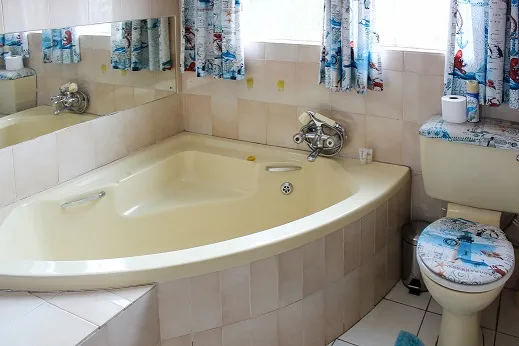 Corner bathtub and toilet in a bathroom with nauticalthemed curtains