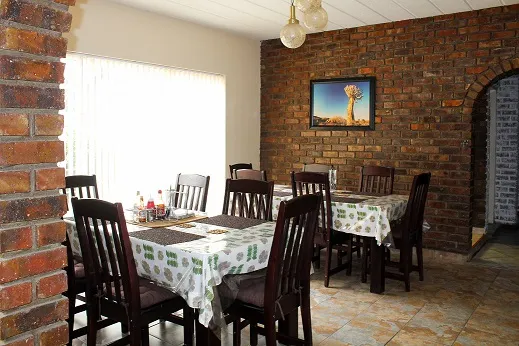 Dining area with wooden tables chairs and a brick wall with a painting