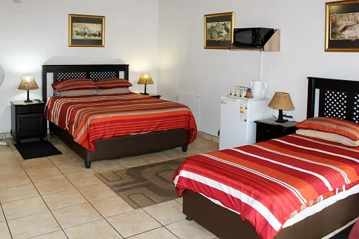 Two beds with red and orange striped bedding in a tidy bedroom