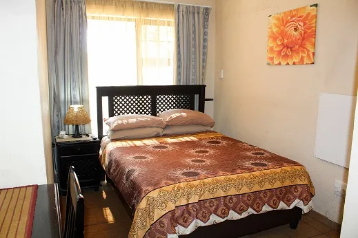 Bedroom with a double bed colorful bedspread and a window with curtains