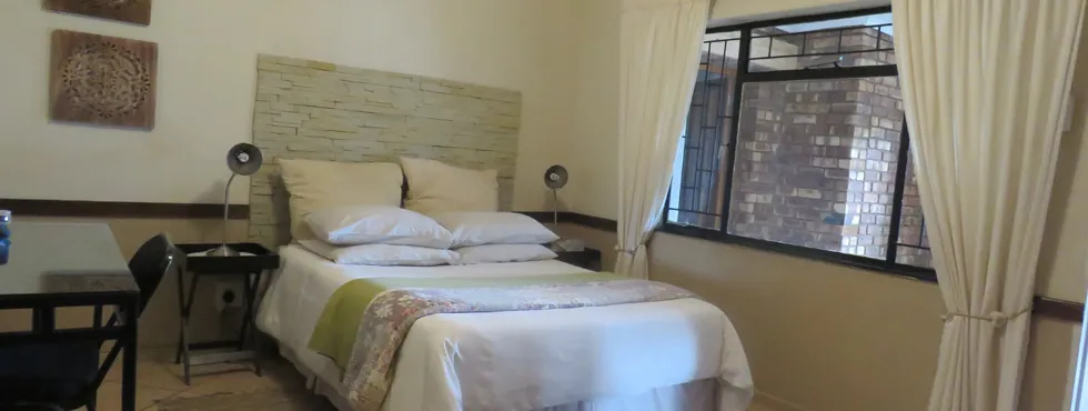 Bedroom with a neatly made bed bedside tables and a window with curtains