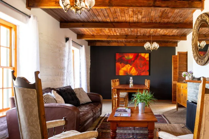 Cozy living room with wooden ceiling leather sofa and dining area in background