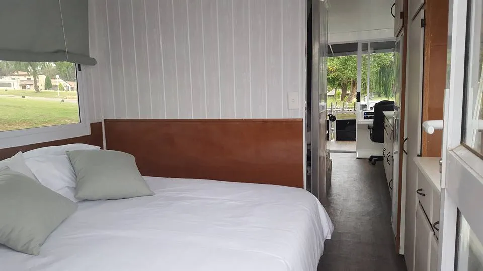 Bedroom with bed window and view of living area in a narrow space