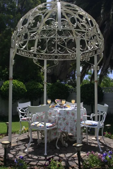 Ornate metal gazebo with table and chairs set for tea in garden