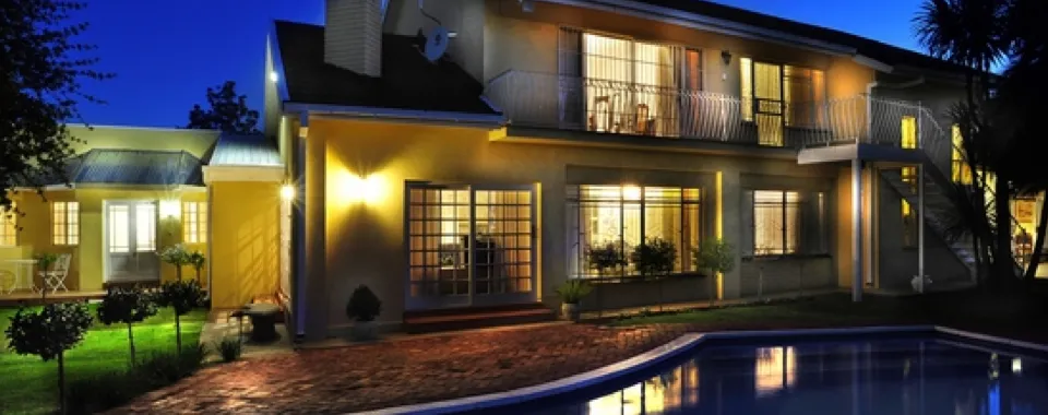 Modern house with pool at night warmly lit windows and garden