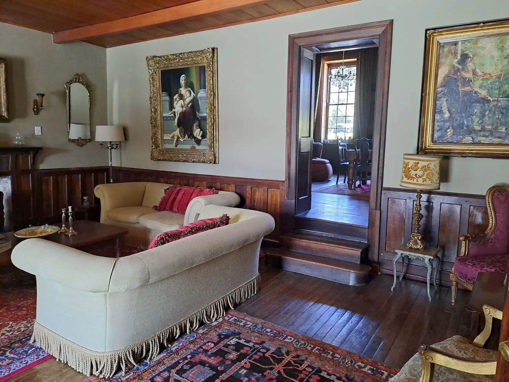 Cozy living room with ornate paintings vintage furniture and wooden paneling