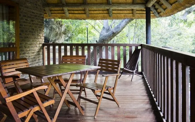 Wooden furniture on a deck overlooking a lush green forest