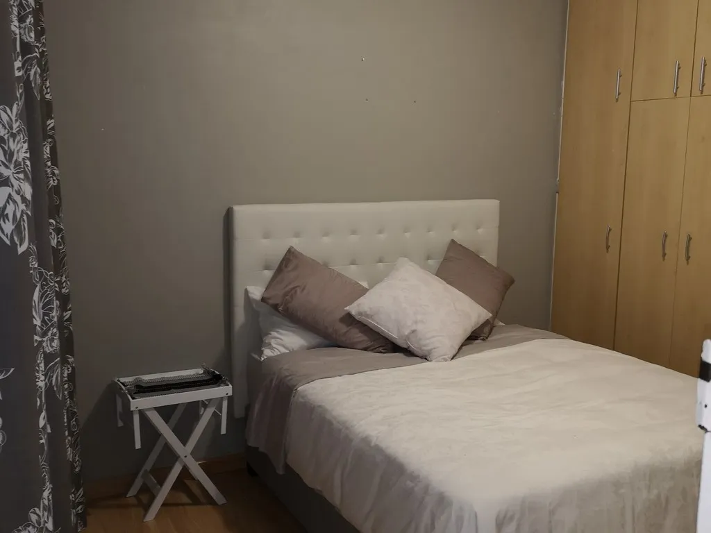 Bedroom with a neatly made bed side table and wooden wardrobe