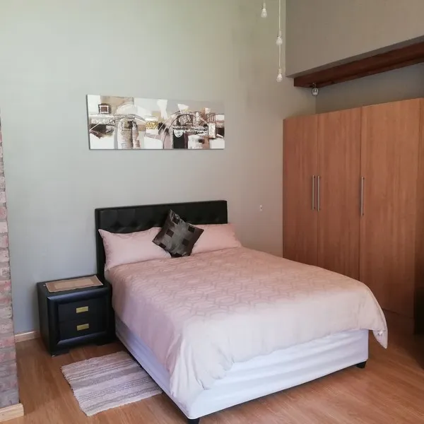 Bedroom with double bed wooden wardrobe and wall art