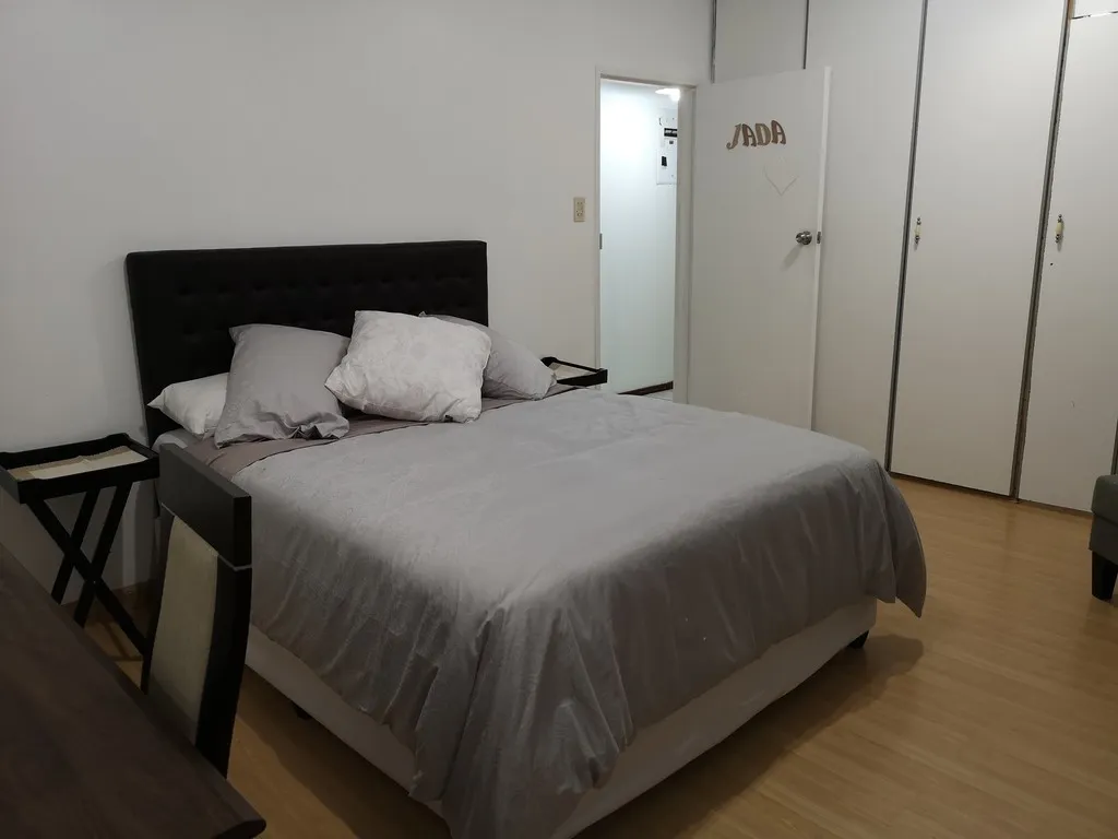 Bedroom with a large bed pillows side tables and wooden flooring