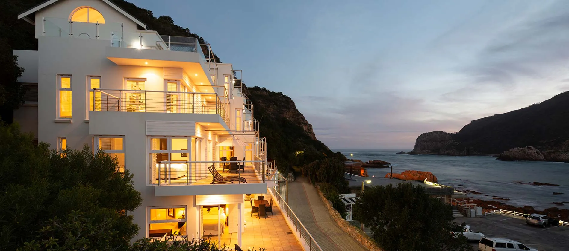 Modern white building on a cliff overlooking the ocean at dusk