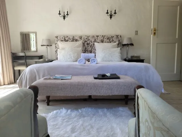Cozy bedroom with a large bed bench and two armchairs on a rug