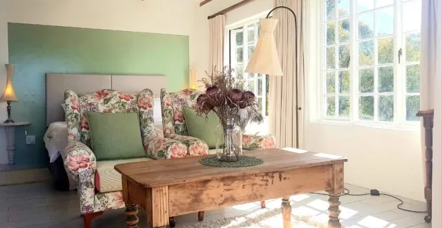 Floral armchairs wooden coffee table and floor lamp in a sunlit living room