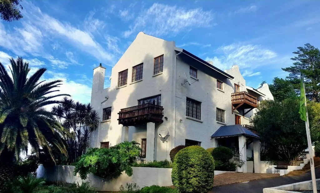 White house with balconies and palm trees in a sunny garden setting