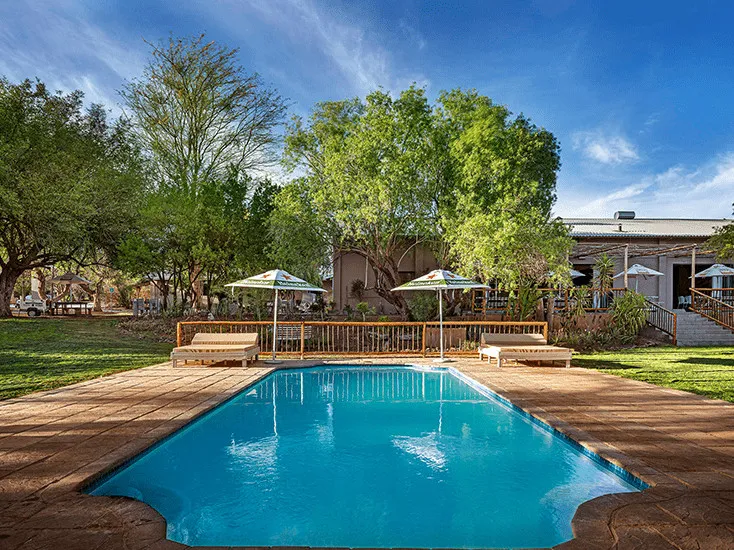 Swimming pool with lounge chairs and umbrellas in a lush garden setting