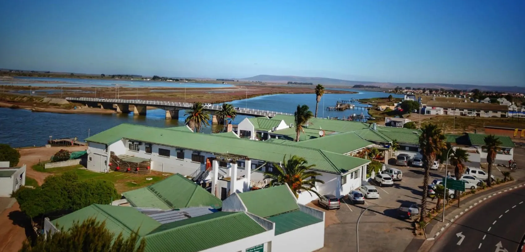 Aerial view of a coastal town with buildings palm trees and a bridge