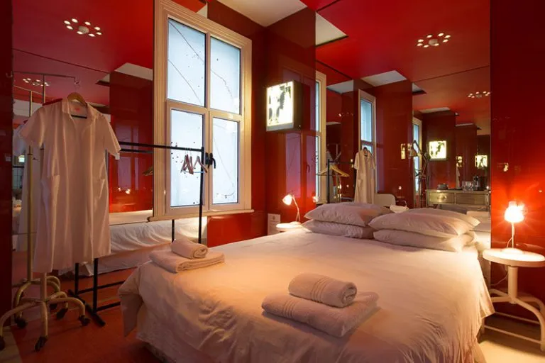 Cozy bedroom with red walls white bed and mirrored wardrobe
