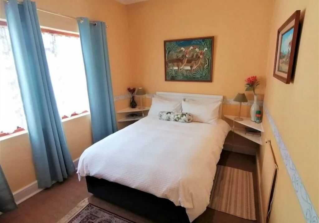 Cozy bedroom with a double bed peach walls and blue curtains