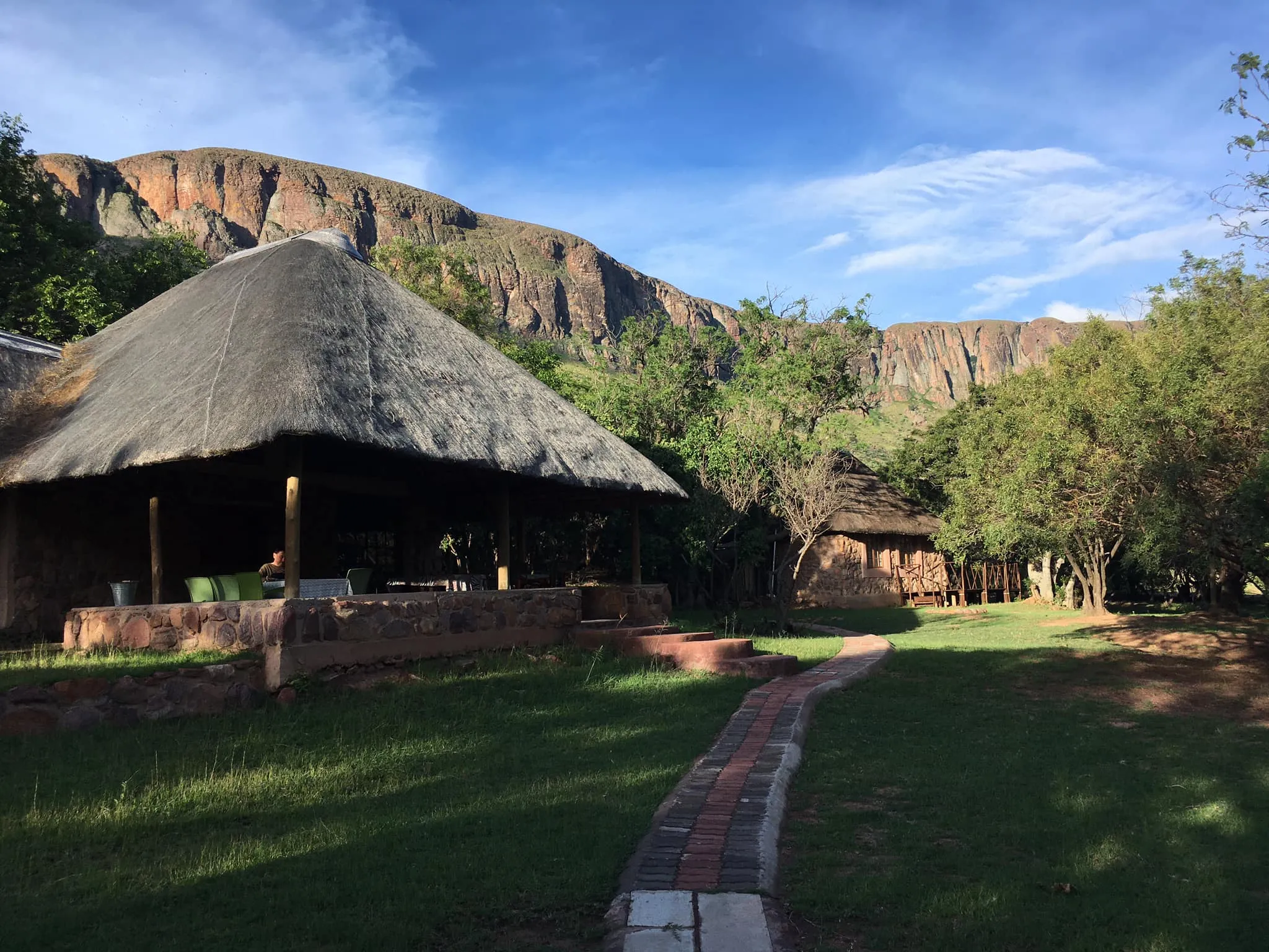 Thatchedroof huts in a lush valley with mountains in the background