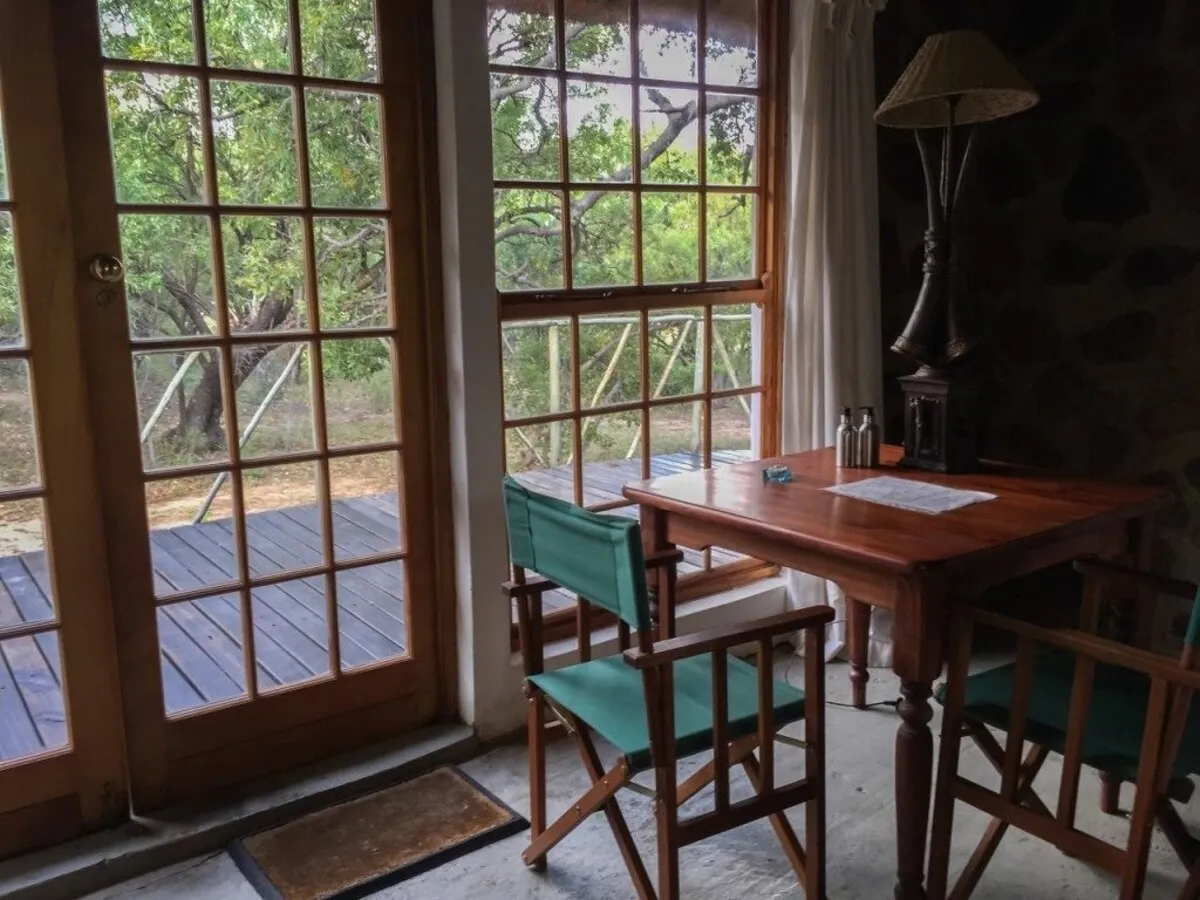 Wooden deck with chairs and table inside a room with large windows