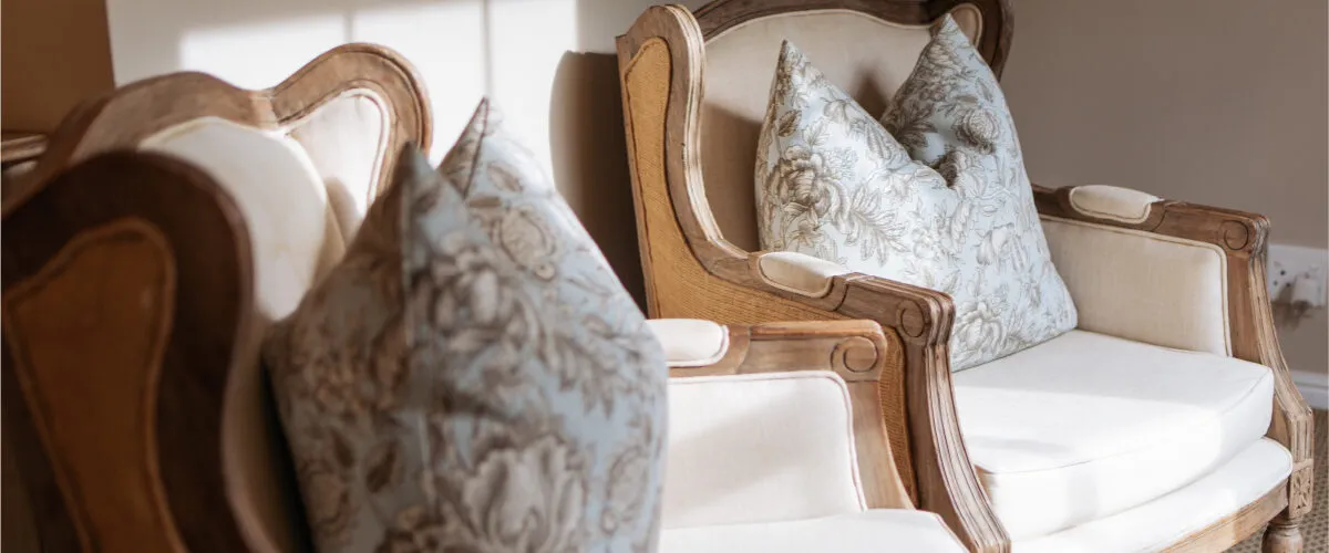 Two ornate wooden chairs with floral cushions in a welllit room