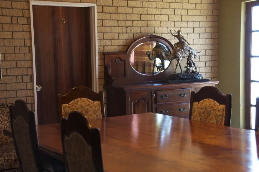 Wooden dining table with chairs sideboard and sculpture in a brickwalled room