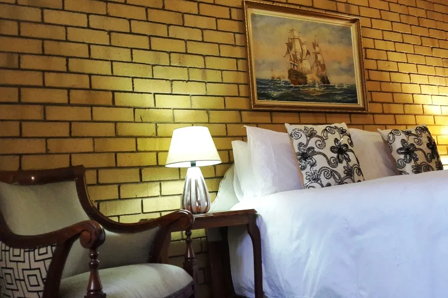 Bedroom with yellow brick wall two armchairs lamp and bed with decorative pillows