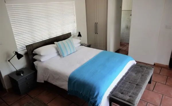 Bedroom with double bed blue blanket bedside tables and tiled floor