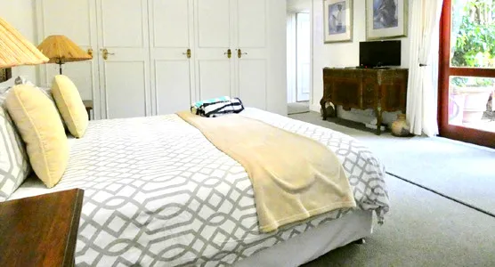 Bedroom with large bed white patterned bedding and sliding glass door to patio