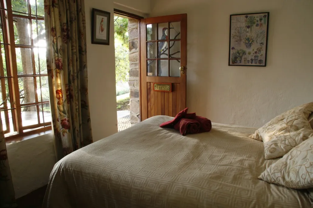 Bedroom with a neatly made bed floral curtains and an open wooden door