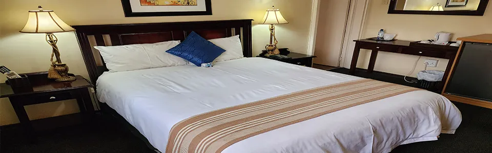 Neatly made bed in a hotel room with bedside tables and lamps