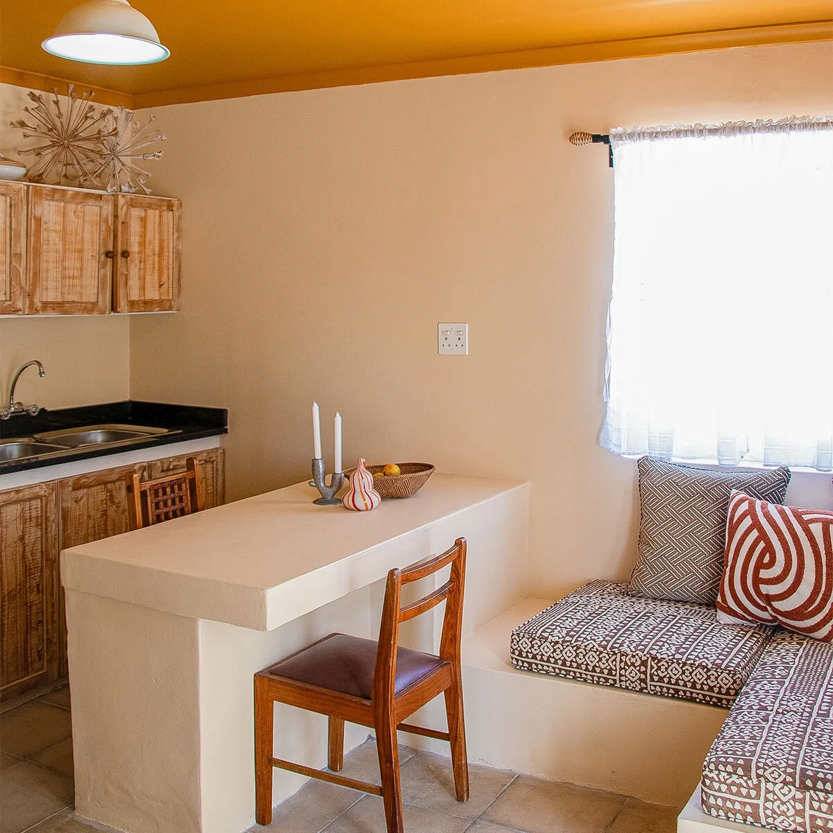 Cozy kitchenette with wooden cabinets countertop and seating area with cushions