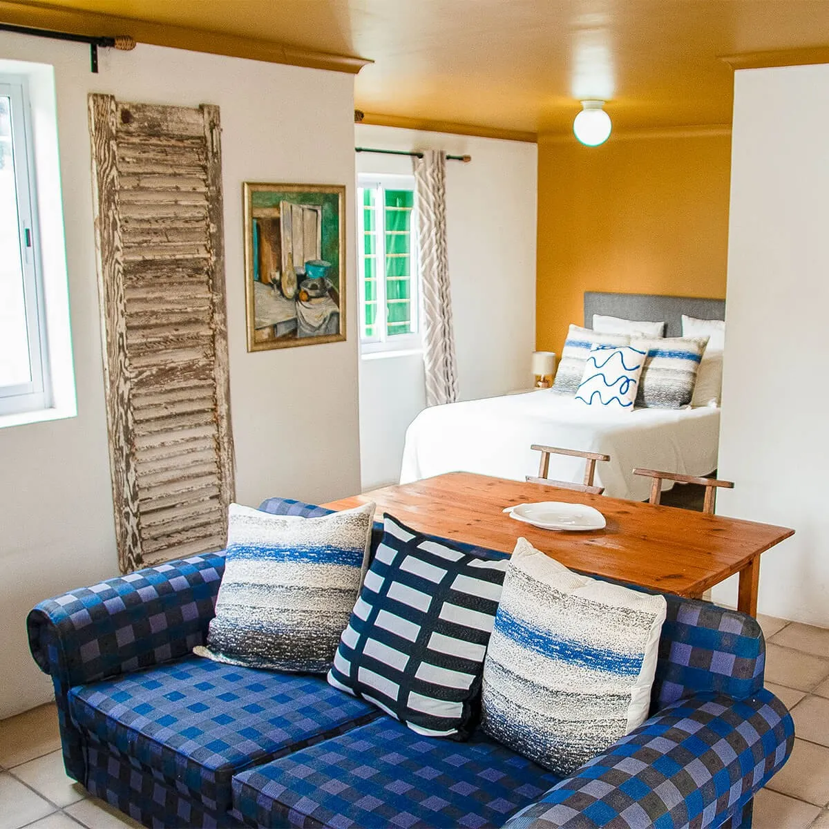 Cozy bedroom with blue plaid sofa wooden table and white bed with pillows