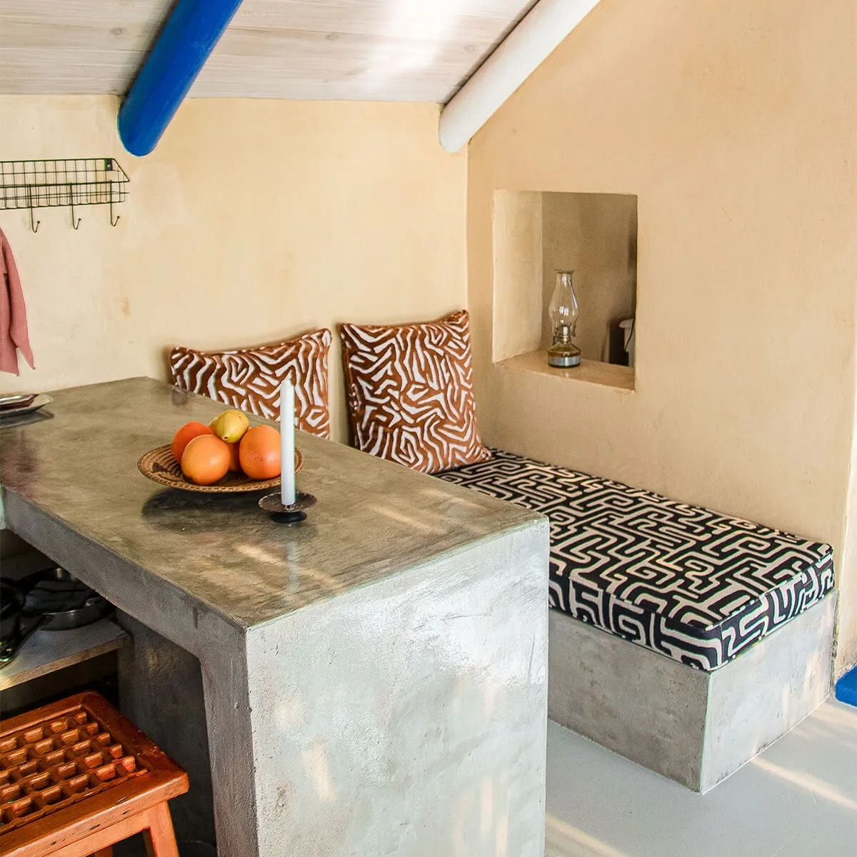 Concrete kitchen counter with fruit pillows on bench and lantern in wall niche