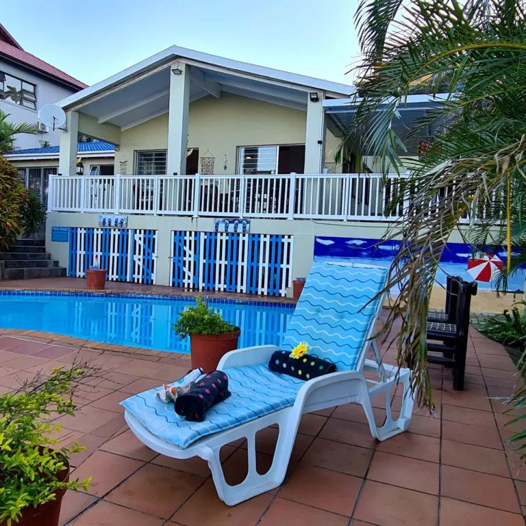 Swimming pool with lounge chair and potted plants in a backyard setting