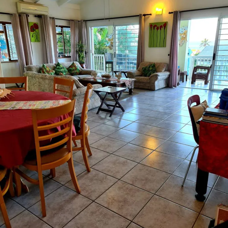 Bright living room with red dining table sofas and open sliding doors to patio