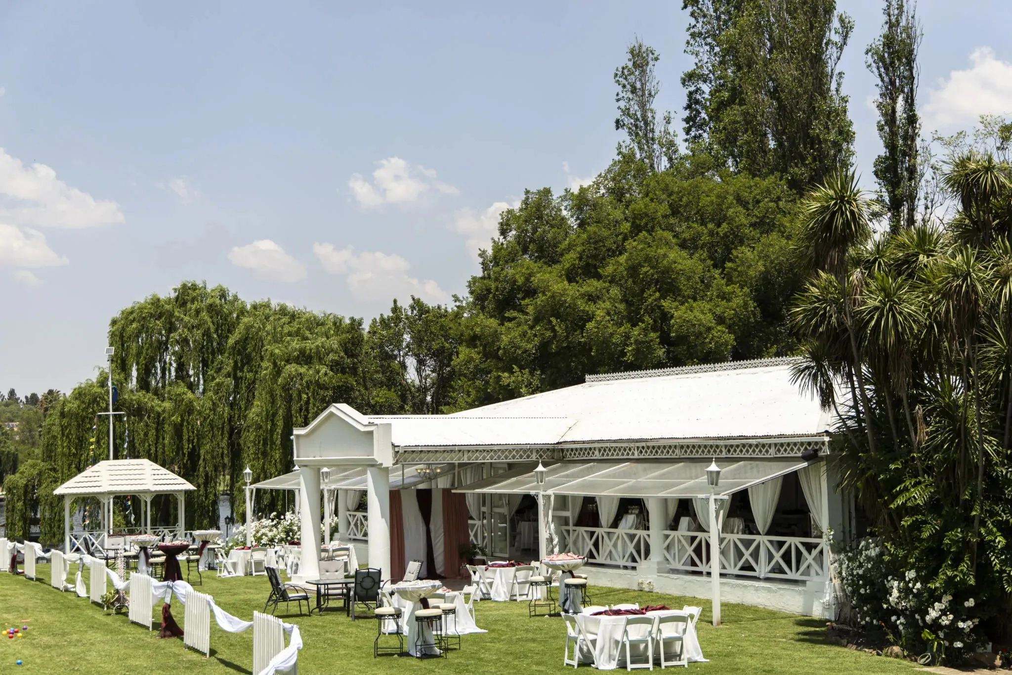 White outdoor event venue with tables and chairs set up on green lawn