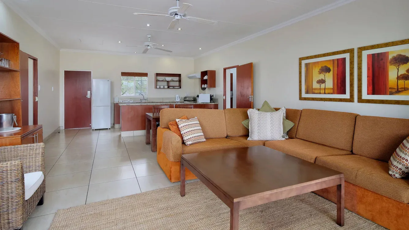 Open living room with sofa coffee table kitchen and ceiling fans